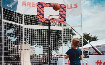 Ein blonder Junge in dunklem Shirt wirft einen Basketball in den Korb (Foto)